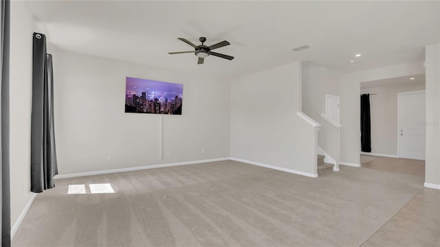 empty room with visible vents, a ceiling fan, baseboards, light colored carpet, and stairs