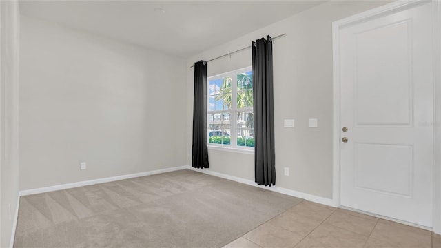 empty room with light tile patterned floors, baseboards, and light carpet