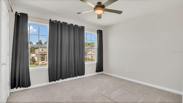 carpeted spare room featuring baseboards and ceiling fan