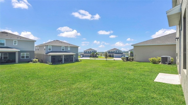 view of yard with a residential view, central AC, and a sunroom