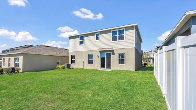 back of house featuring central AC unit, a yard, and stucco siding