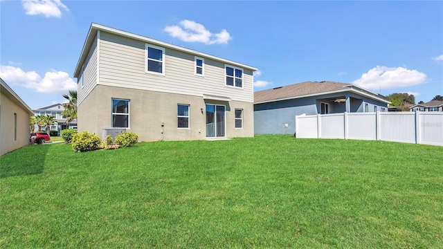 back of property with a yard, fence, and stucco siding