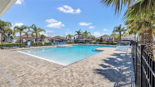 pool with a patio area, a residential view, and fence