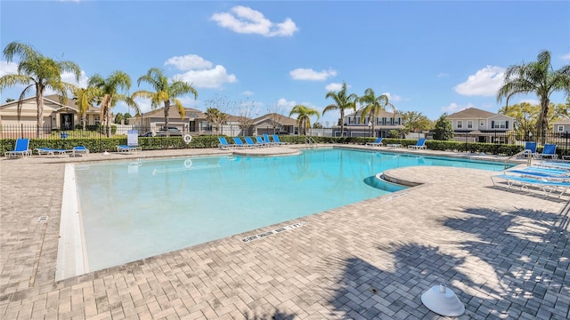 community pool with a residential view, a patio, and fence