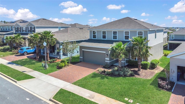 view of front facade featuring a front lawn, decorative driveway, and a shingled roof