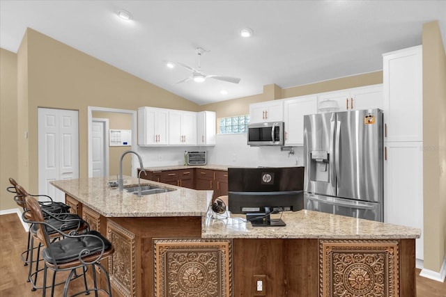 kitchen with a large island with sink, lofted ceiling, stainless steel appliances, a sink, and ceiling fan