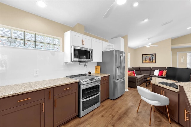 kitchen featuring ceiling fan, appliances with stainless steel finishes, lofted ceiling, white cabinetry, and light wood-style floors