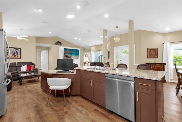 kitchen with open floor plan, vaulted ceiling, light wood-type flooring, stainless steel appliances, and a sink