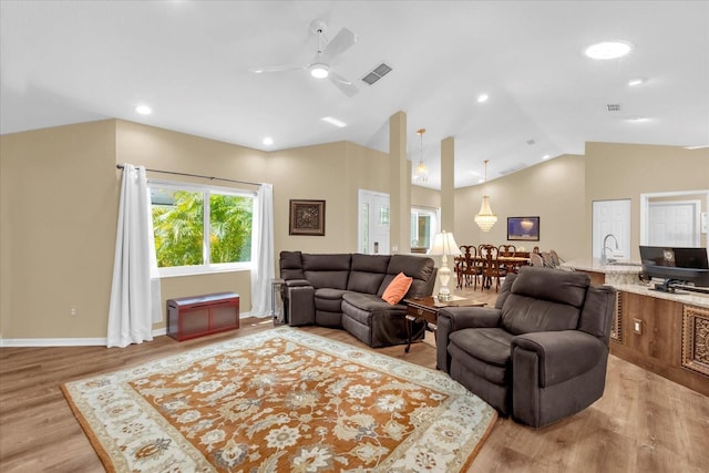 living area featuring vaulted ceiling, light wood-type flooring, baseboards, visible vents, and ceiling fan