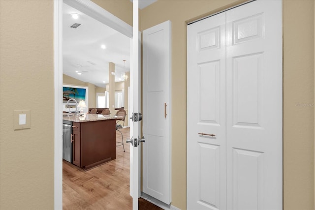 hallway with vaulted ceiling, visible vents, light wood-style flooring, and a sink