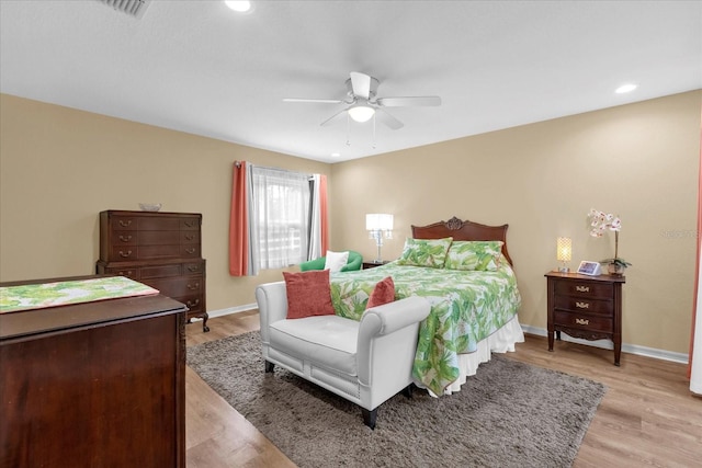 bedroom featuring baseboards, ceiling fan, visible vents, and light wood finished floors