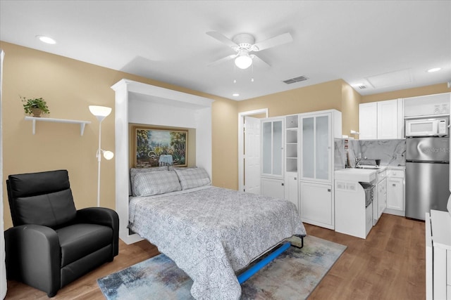 bedroom with attic access, visible vents, wood finished floors, and freestanding refrigerator