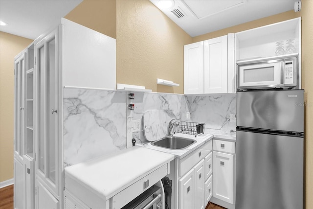 kitchen with white cabinetry, a sink, visible vents, freestanding refrigerator, and white microwave