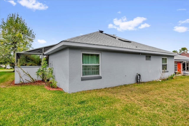 view of side of property featuring roof with shingles, stucco siding, and a yard