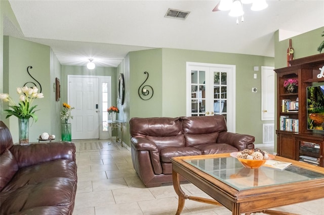 living room with light tile patterned floors, visible vents, and ceiling fan