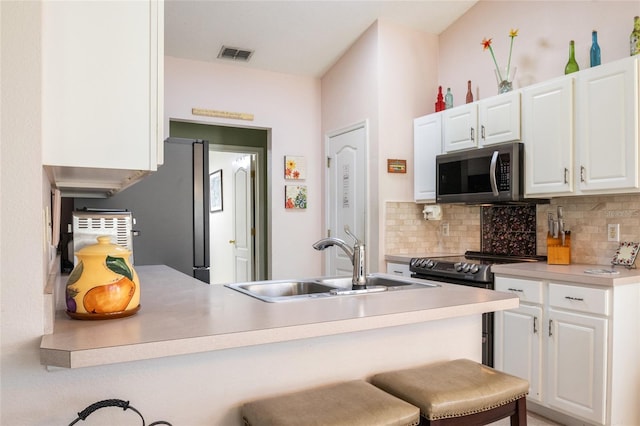 kitchen with a sink, stainless steel appliances, tasteful backsplash, and white cabinetry