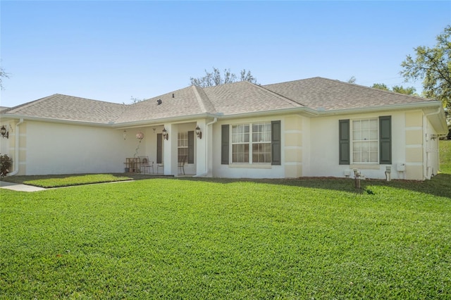 ranch-style home featuring stucco siding, roof with shingles, and a front yard