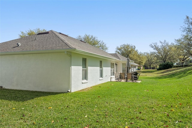 rear view of house featuring a yard, a patio, stucco siding, and a shingled roof