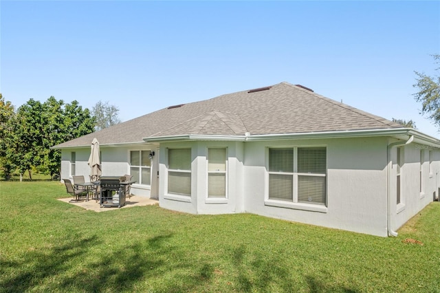 rear view of house featuring a shingled roof, a patio area, stucco siding, and a lawn