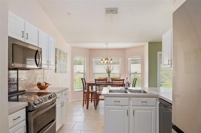 kitchen featuring a sink, a peninsula, decorative backsplash, stainless steel appliances, and white cabinets