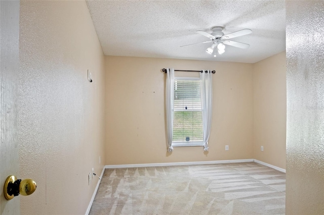 empty room featuring ceiling fan, a textured ceiling, carpet flooring, and baseboards