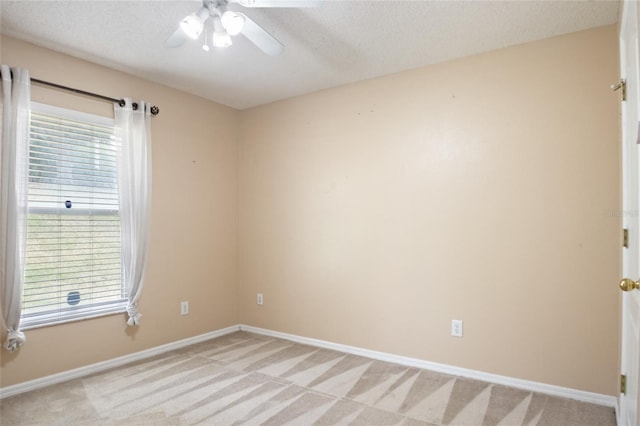 empty room with light carpet, baseboards, and a ceiling fan