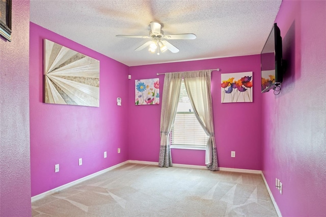 empty room with carpet, baseboards, ceiling fan, and a textured ceiling