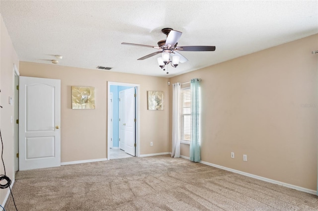 carpeted empty room with a textured ceiling, visible vents, baseboards, and ceiling fan