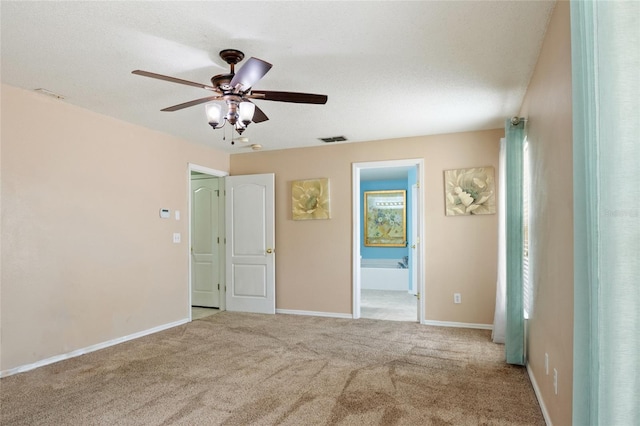 carpeted spare room with baseboards, ceiling fan, and visible vents