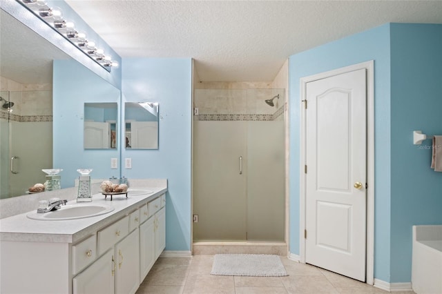 full bathroom with a shower stall, a sink, double vanity, and a textured ceiling