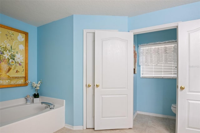 bathroom featuring toilet, baseboards, a bath, and tile patterned floors