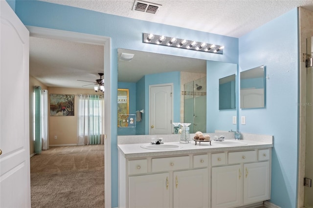 bathroom featuring a shower stall, ceiling fan, visible vents, and a sink