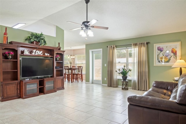 living room with lofted ceiling, ceiling fan with notable chandelier, baseboards, and light tile patterned floors