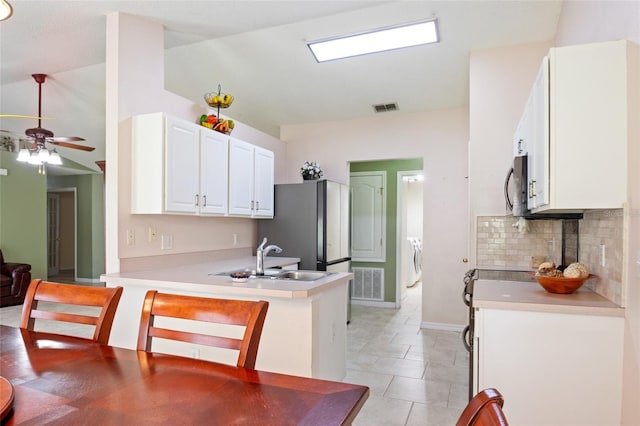 kitchen featuring a peninsula, a ceiling fan, a sink, visible vents, and stainless steel microwave