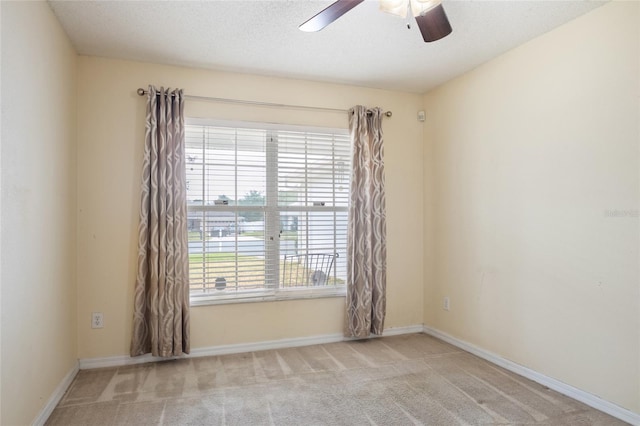 carpeted empty room featuring baseboards and ceiling fan
