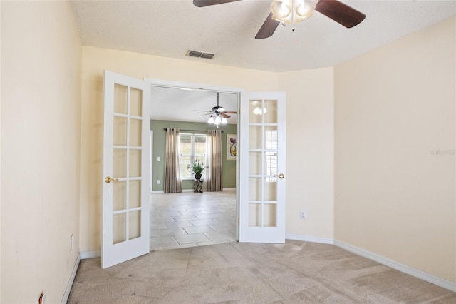 carpeted empty room featuring ceiling fan, baseboards, french doors, and visible vents