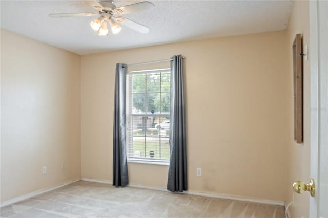 spare room with light colored carpet, baseboards, and ceiling fan