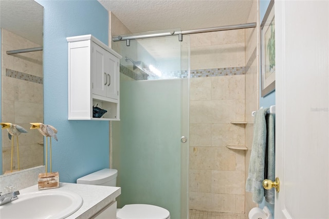 bathroom featuring a shower stall, vanity, toilet, and a textured ceiling