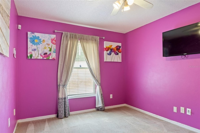 empty room featuring a textured ceiling, carpet floors, a ceiling fan, and baseboards