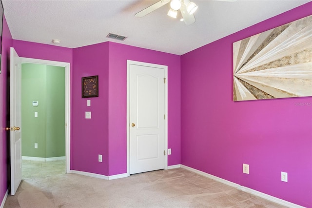 unfurnished bedroom featuring carpet flooring, visible vents, baseboards, and a ceiling fan
