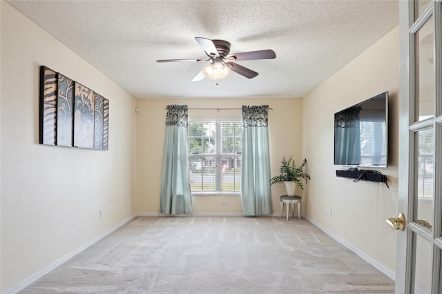 carpeted empty room featuring a textured ceiling, baseboards, and a ceiling fan