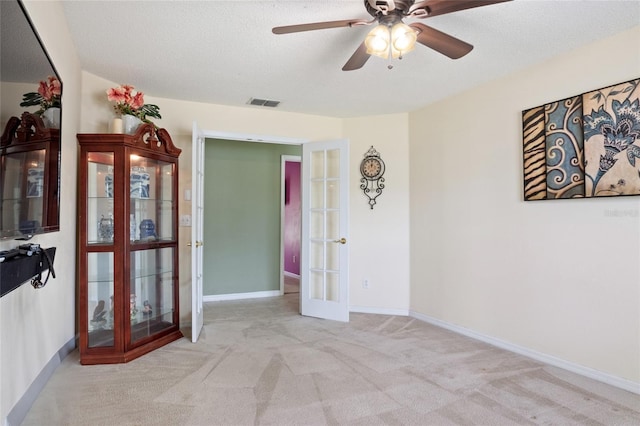carpeted spare room featuring a ceiling fan, visible vents, french doors, and baseboards