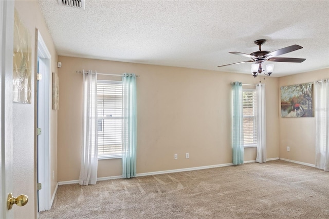 carpeted empty room with baseboards, visible vents, ceiling fan, and a textured ceiling
