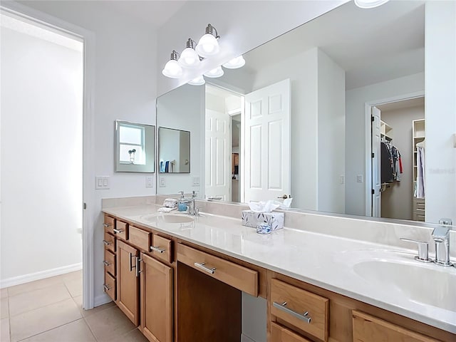 bathroom with tile patterned flooring, vanity, a walk in closet, and baseboards