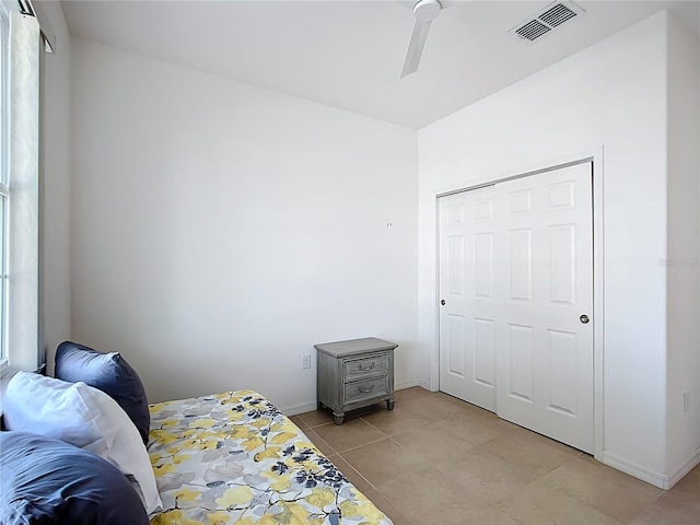 bedroom with visible vents, a closet, light tile patterned floors, baseboards, and ceiling fan