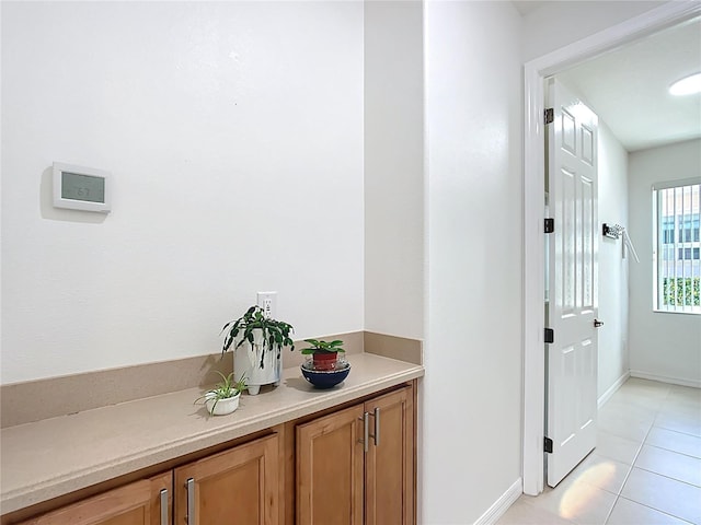 corridor featuring light tile patterned floors and baseboards