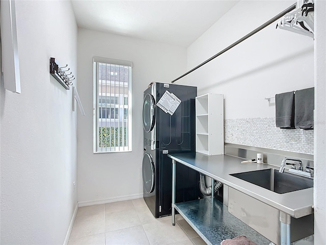 washroom with a sink, stacked washing maching and dryer, tile patterned flooring, baseboards, and laundry area