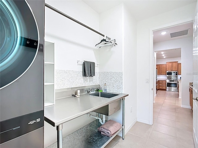 interior space featuring visible vents, brown cabinets, stacked washer and dryer, a sink, and decorative backsplash