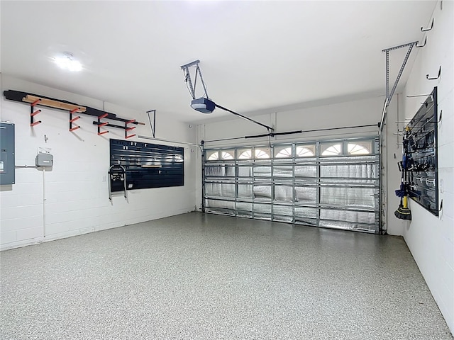 garage with concrete block wall, electric panel, and a garage door opener