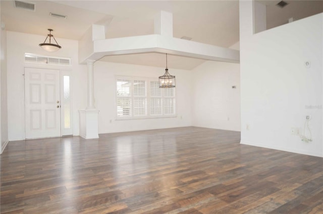 entrance foyer featuring visible vents, an inviting chandelier, wood finished floors, and decorative columns